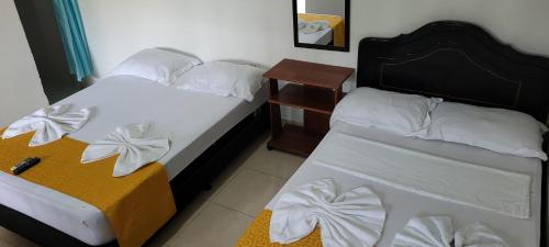 a bedroom with two beds and a night stand with a bedskirts at Hostal Villa del Río Las Brisas in Villavieja