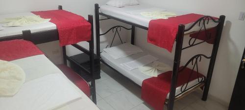 a room with two bunk beds with red sheets at Hostal Villa del Río Las Brisas in Villavieja