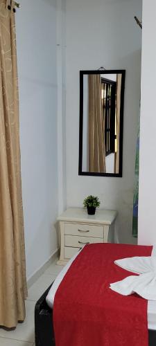 a bedroom with a red bed and a mirror at Hostal Villa del Río Las Brisas in Villavieja