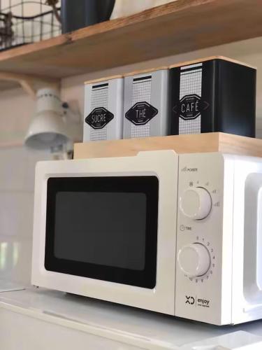 a white microwave sitting on a counter with a shelf at fattoria Coppetella Cemani in Molino dʼAgugliano