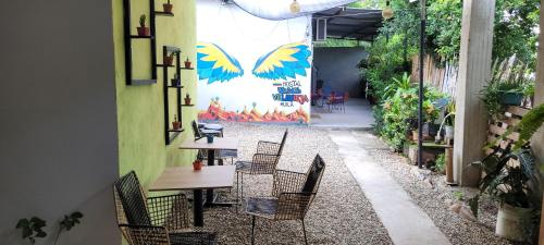 a patio with chairs and tables and a wall with a mural at Hostal Villa del Río Las Brisas in Villavieja