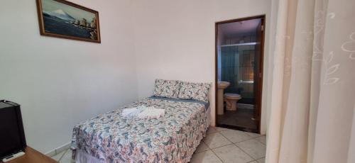 a bedroom with a bed and a chair in a room at Hospedagem Familiar Yamane in Ilha Comprida
