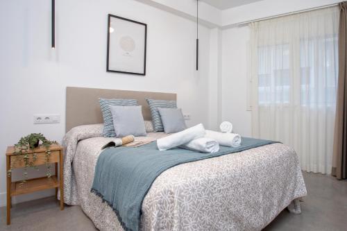 a bedroom with a bed with blue and white blankets and pillows at Apartamentos Costa Tropical by Rent Me in Motril