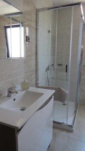 a white bathroom with a sink and a shower at Casa da Calçada - Piso 1 in Seia