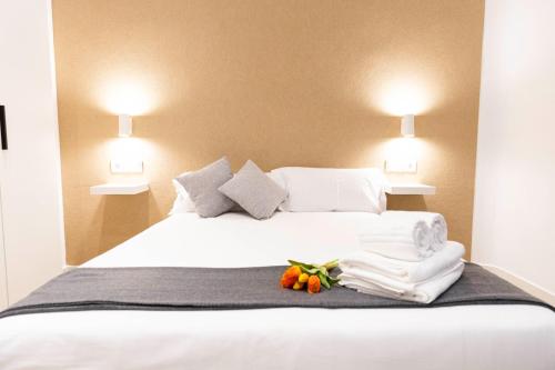 a large white bed with towels and flowers on it at Apartamentos Julio Burell, 74 CAROLA in Linares