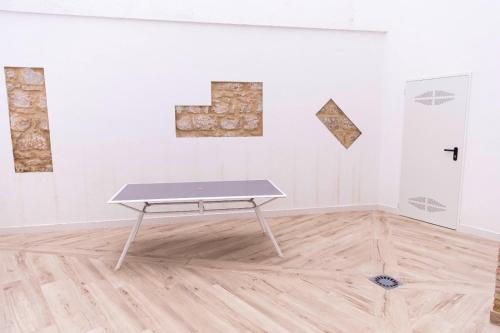 a table in front of a white wall with paintings at Apartamentos Julio Burell, 74 CAROLA in Linares
