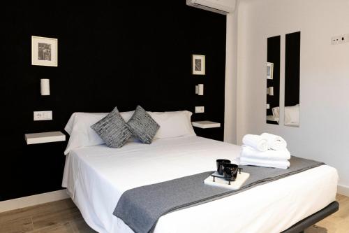 Un dormitorio con una cama blanca con una pared negra. en Apartamentos Julio Burell, 74, en Linares