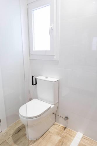 a white toilet in a bathroom with a window at Apartamentos Julio Burell, 74 CAROLA in Linares