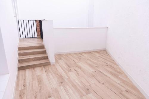 a staircase in a white room with wooden floors at Apartamentos Julio Burell, 74 CAROLA in Linares