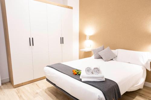 a bedroom with a large white bed with towels on it at Apartamentos Julio Burell, 74 CAROLA in Linares