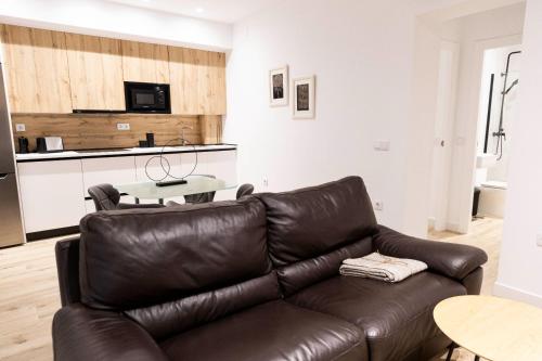 a brown leather couch in a living room with a table at Apartamentos Julio Burell, 74 CAROLA in Linares