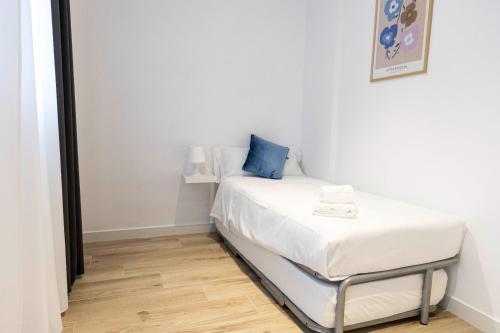a small bedroom with a bed with a blue pillow at Apartamentos Julio Burell, 74 CAROLA in Linares