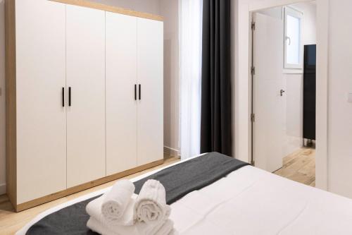 a white bedroom with white cabinets and white towels on a bed at Apartamentos Julio Burell, 74 CAROLA in Linares
