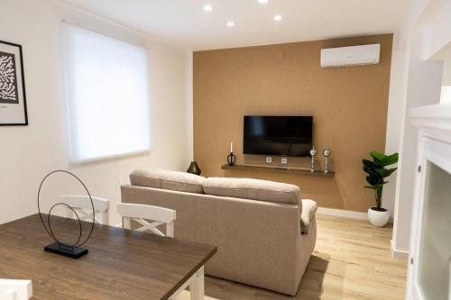 a living room with a couch and a tv on a wall at Apartamentos Julio Burell, 74 CAROLA in Linares