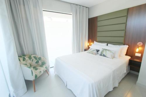 a bedroom with a white bed and a chair at Pousada São Gerônimo in Matinhos