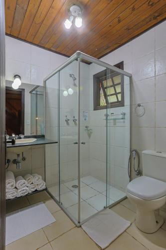a bathroom with a glass shower with a toilet at Pousada Cantos e Contos in Monte Verde