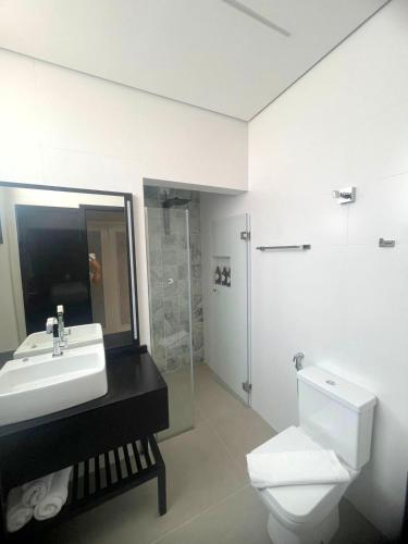 a white bathroom with a sink and a toilet at Pousada Cancun Boutique in Guarujá