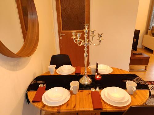 a wooden table with white plates and a candlestick at Cozy Independent House with Free Parking and 20 mins to center in Helsinki