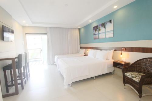 a bedroom with two beds and a table and a chair at Pousada São Gerônimo in Matinhos