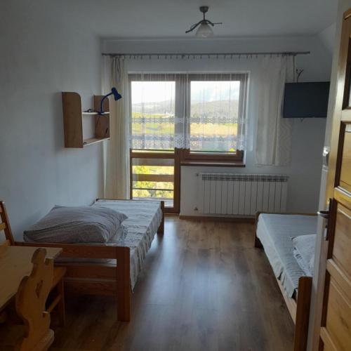 a bedroom with two beds and a window at Wynajem Pokoi Maria Sowińska in Biały Dunajec