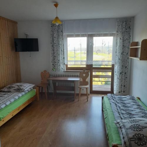 a bedroom with two beds and a table and a window at Wynajem Pokoi Maria Sowińska in Biały Dunajec