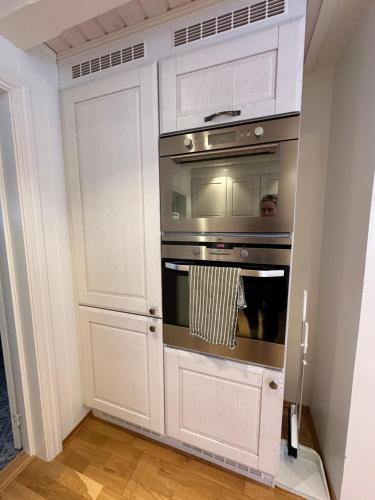 a kitchen with an oven and white cabinets at Marisletta farm - house by the sea in Tromsø