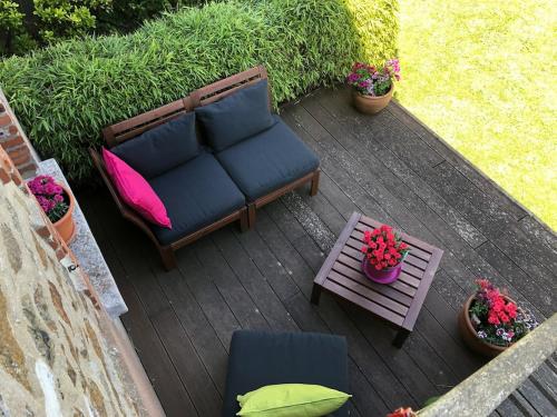 a patio with a couch and a table and flowers at Les Hauts du Tertre Notre Dame in Saint-Brieuc