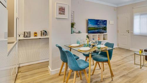 a dining room with a table and blue chairs at Coral Apartment La Cala Beach in La Cala de Mijas