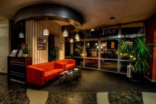 a living room with an orange couch and a table at Aviator Hotel Restauracja & SPA in Pabianice