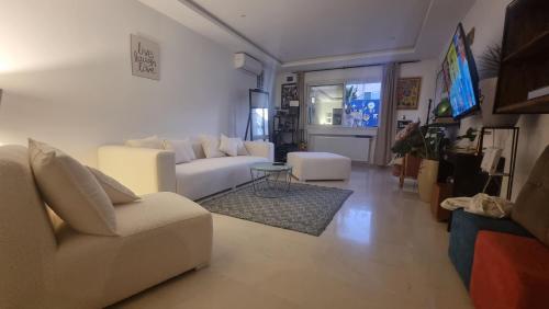 a living room with a white couch and a tv at Ghamarth Mikonos in Gammarth