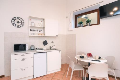 eine Küche mit weißen Schränken und einem Tisch mit Stühlen in der Unterkunft Giada 103 - Central Florence Apartment by the train station in Florenz