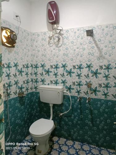 a bathroom with a toilet and green and white wallpaper at Hotel O Mahavir Guest House in Cuttack