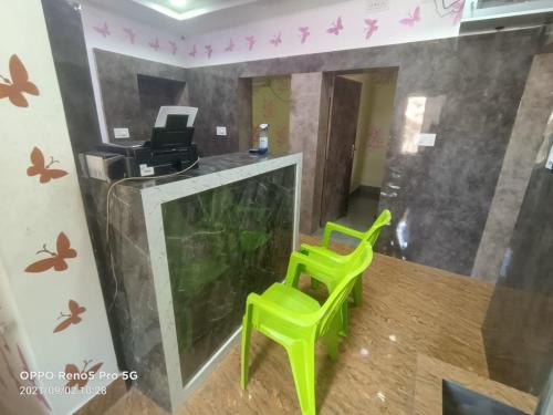 two green chairs in an office with butterflies on the wall at Hotel O Mahavir Guest House in Cuttack