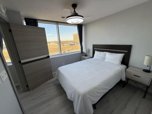 a bedroom with a white bed and a large window at Modern High-Rise Apartment - 4 in Tulsa