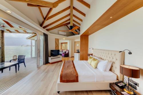 a bedroom with a bed and a view of the ocean at Cinnamon Dhonveli Maldives in North Male Atoll