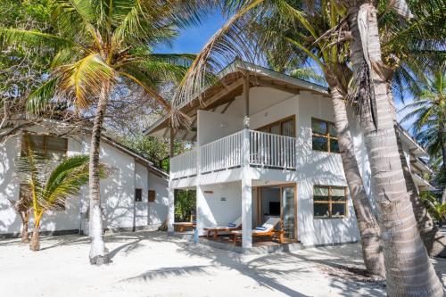 a house on the beach with palm trees at Cinnamon Dhonveli Maldives in North Male Atoll