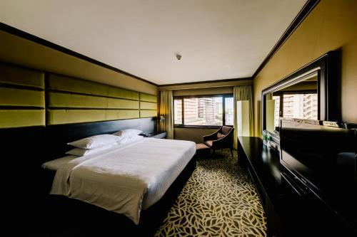 a hotel room with a large bed and a desk at Cinnamon Lakeside in Colombo
