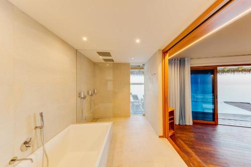 a bathroom with a bath tub and a window at Cinnamon Velifushi Maldives in Keyodhoo
