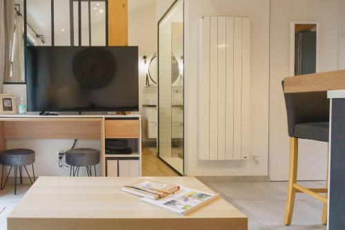a living room with a television and a table at Cocon Classé 3 Etoiles - Love et Détente - SPA in Carpentras
