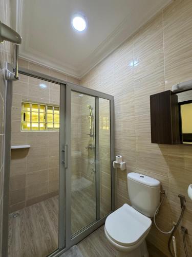 a bathroom with a toilet and a glass shower at Résidence TK House in Cotonou