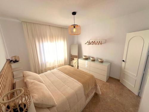 a white bedroom with a bed and a chandelier at Rincón Del Sol in Frigiliana