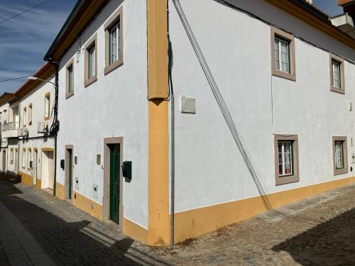 a white building with a green door on a street at Alojamentos Vila Alpalhão in Alpalhão