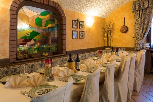 a dining room with a long table with white chairs at Hotel Aurora in Cimego