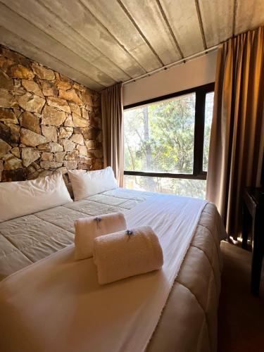 a bed in a room with two towels on it at Village de las Pampas Apart Hotel Boutique in Mar de las Pampas