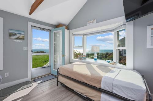 a bedroom with a bed and two large windows at Seaside Cottages - Cottage 32B - Seaside One and Too in South Yarmouth