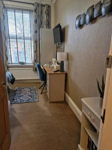a room with a desk with a computer and a window at Warwick Lodge in Carlisle