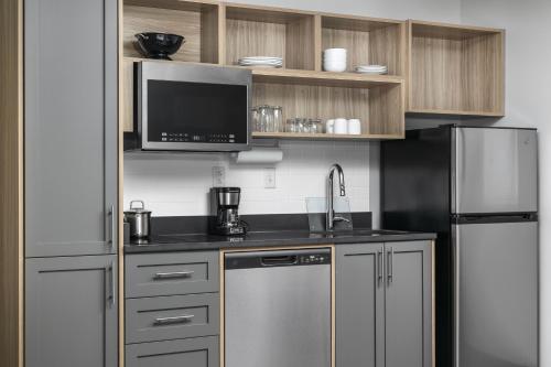 a kitchen with a stainless steel refrigerator and a microwave at Candlewood Suites Chattanooga Hamilton Place by IHG in Chattanooga