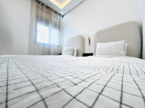 a bedroom with a large white bed with a window at Elegant & Contemporary Stay in Temara