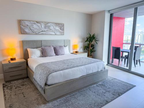 Un dormitorio con una cama grande y un balcón. en Luxury 3 bedroom condo with pool, en Hallandale Beach
