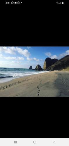 a picture of a beach with footprints in the sand at The Lookout Beach Hotel in San Lorenzo